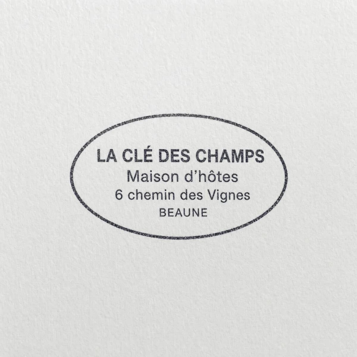 Maison d’hôtes avec cadre ovale : exemple d’empreinte à l’encre noire sur papier blanc