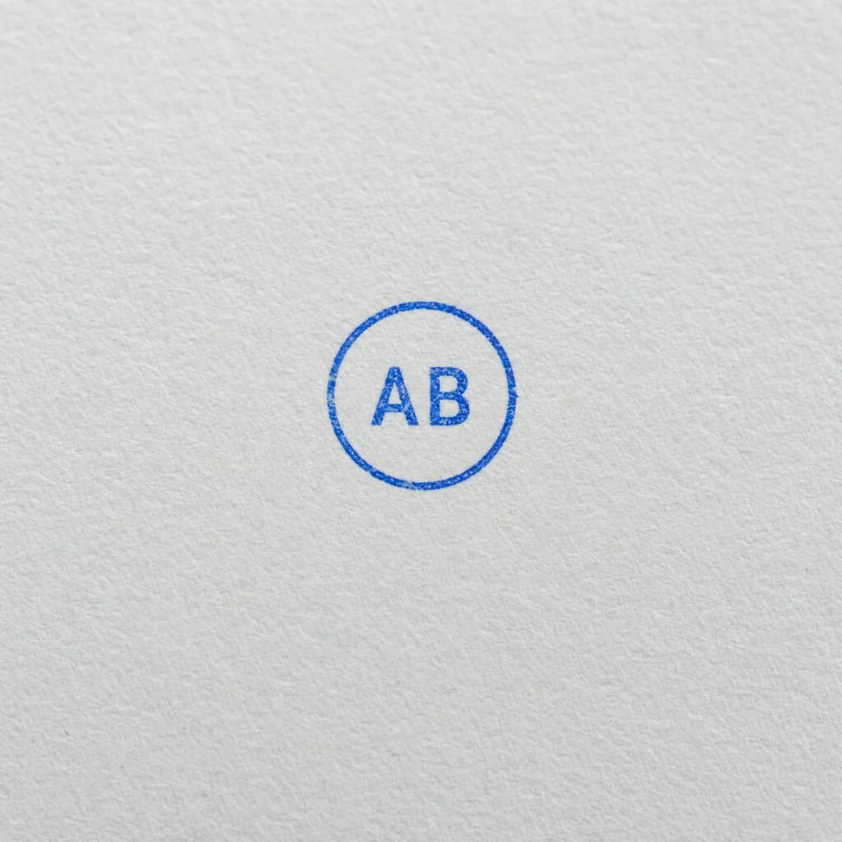 Initiales dans un cercle bleu : exemple d’empreinte à l’encre bleue sur papier blanc