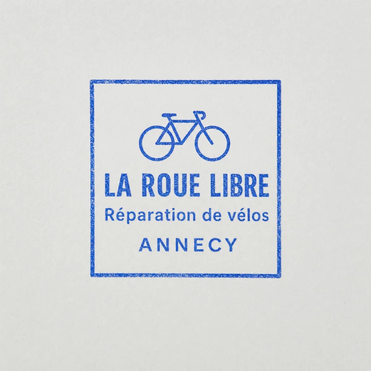 Atelier vélo avec logo : exemple d’empreinte à l’encre bleue sur papier blanc