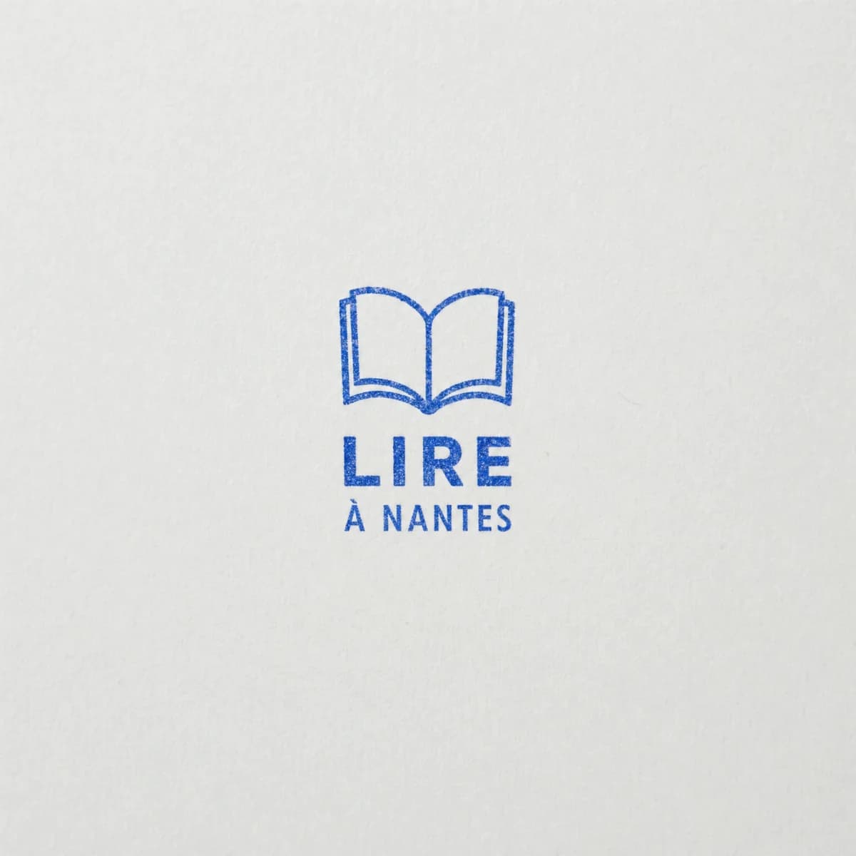 Librairie avec logo de livre : exemple d’empreinte à l’encre bleue sur papier blanc